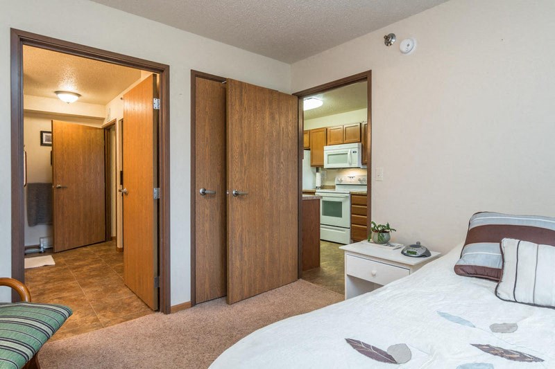 a bedroom with a bed and a closet and a kitchen