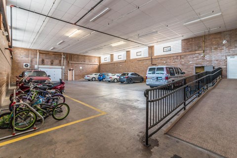 A parking garage with a red car and a white van.