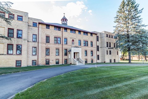 A large building with a clock tower and a tree in front of it.