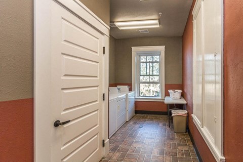 A hallway with a white door and a window with a white chair and a white bucket on the windowsill.