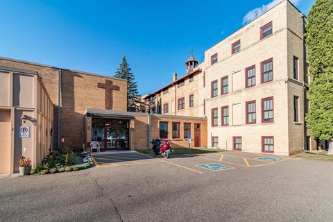 A church with a cross on the building and a parking lot in front.