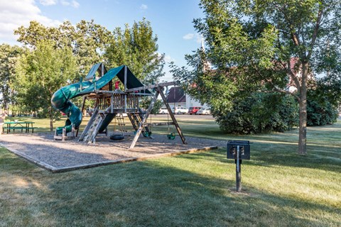 A playground with a green slide and a wooden structure.