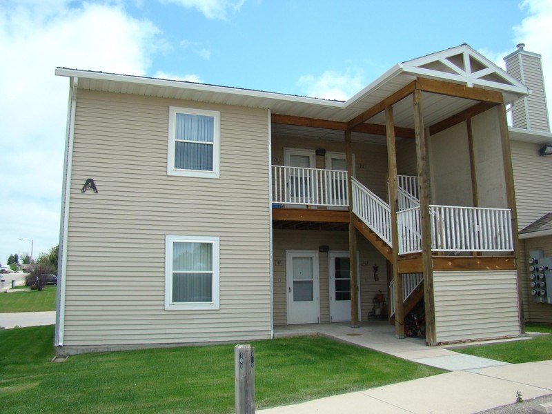 a tan house with a deck and a porch