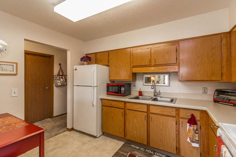 a kitchen with a sink and refrigerator and wooden cabinets