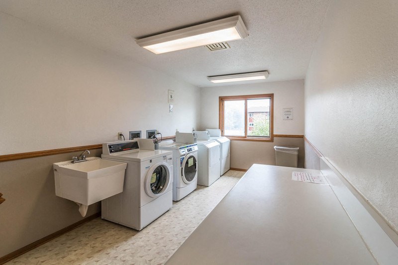 a washer and dryer in a laundry room with a row of washing machines