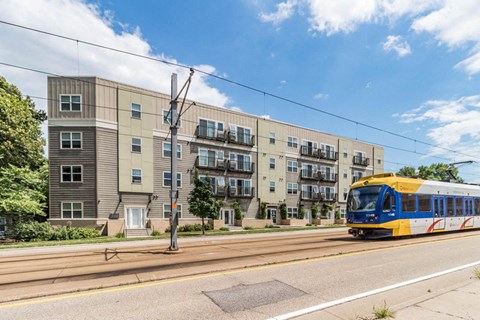 a blue and yellow train traveling past an apartment building