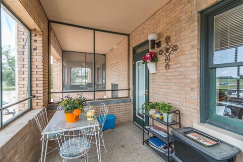 A balcony with a table and chairs and a plant on the side.