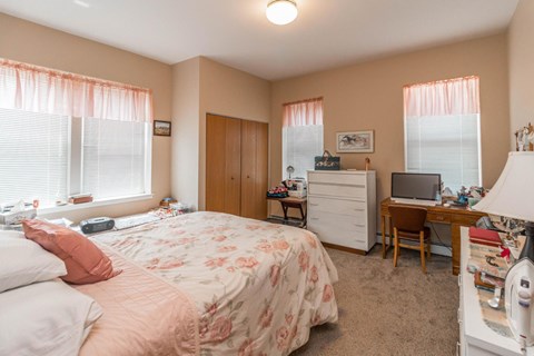 A bedroom with a bed, desk, and chair.