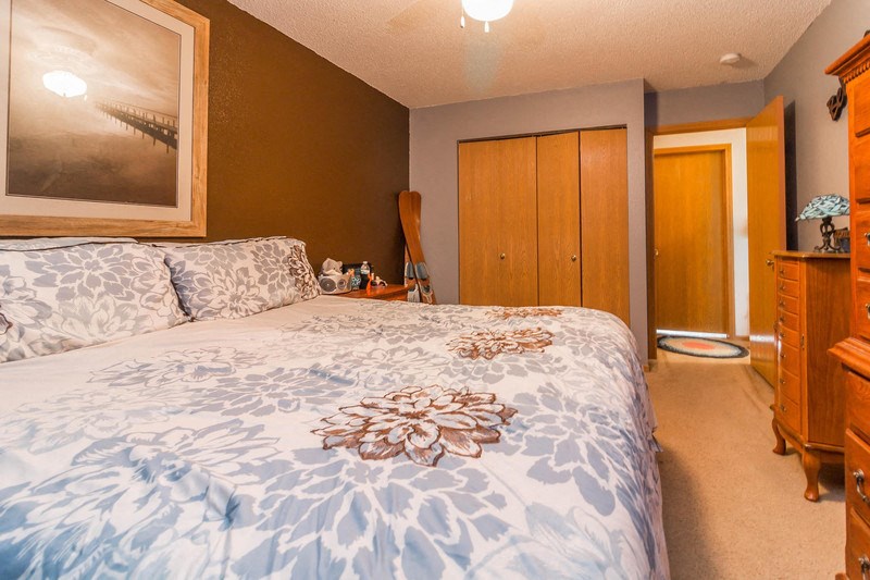 a bedroom with a bed and a dresser and a bathroom