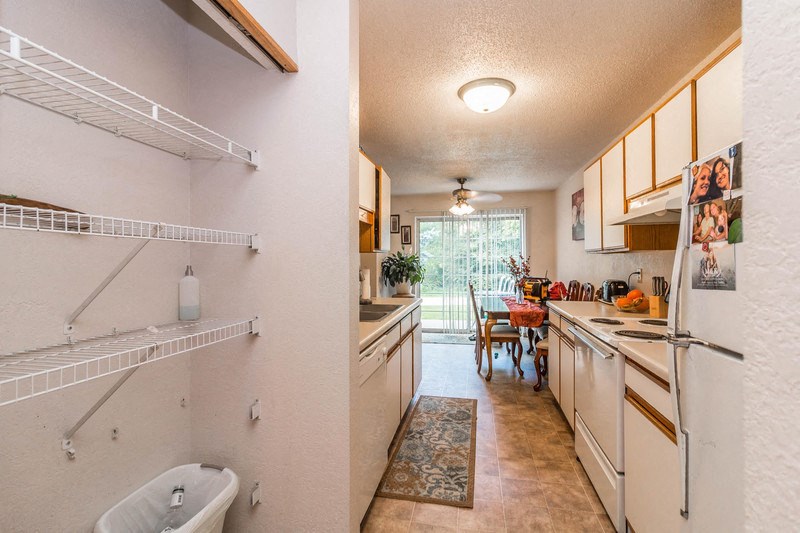the kitchen and dining room of a house with white cabinets and a sink and refrigerator