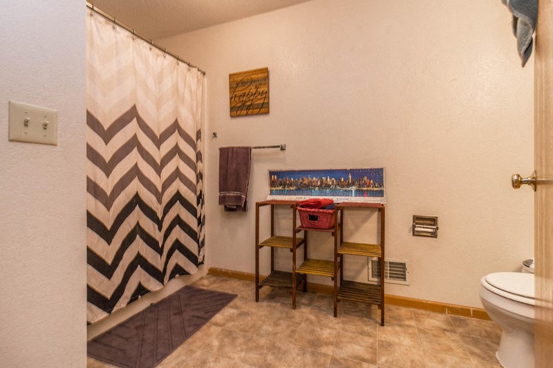 a bathroom with a shower and a sink and a chair