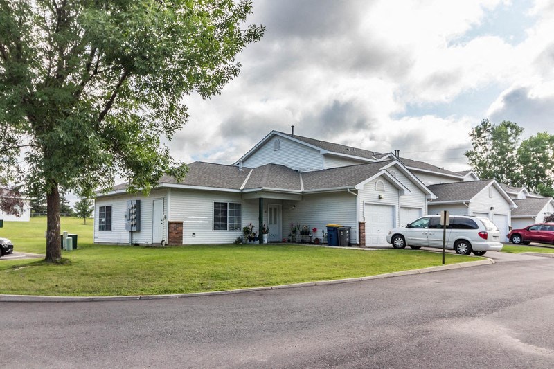 a white house with a yard and cars parked in front of it