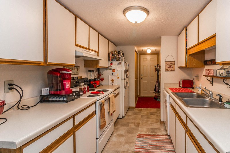 a kitchen with white cabinets and a sink and a refrigerator