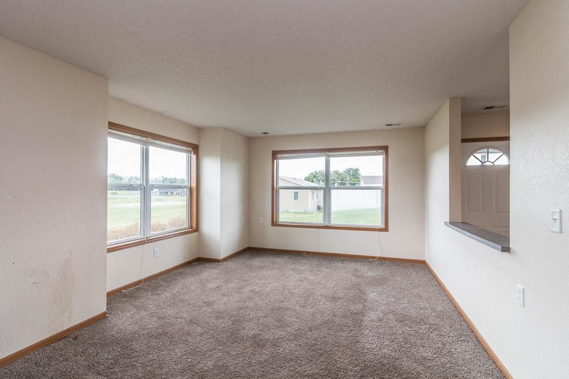 the living room of an empty house with large windows