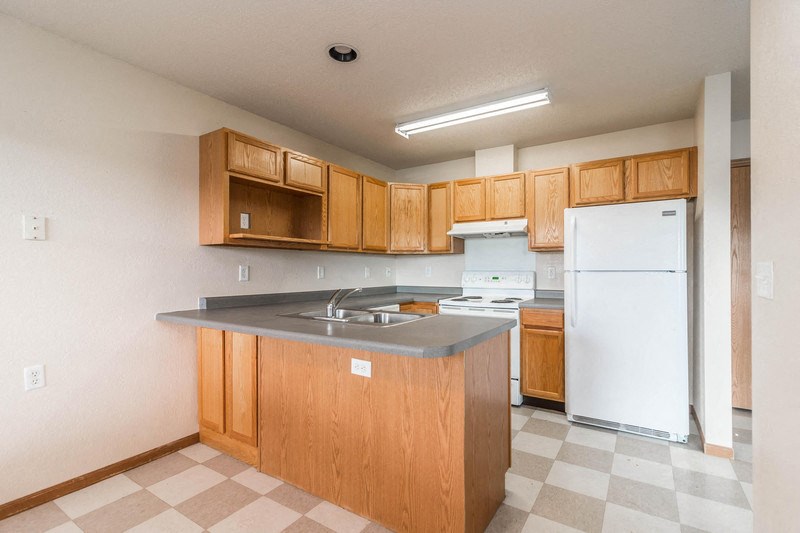an empty kitchen with wooden cabinets and a white refrigerator