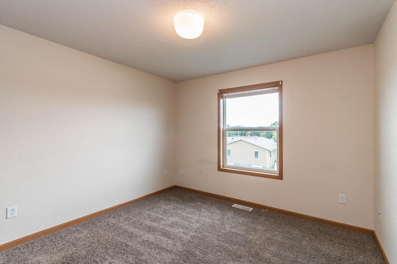 an empty living room with a window and carpet