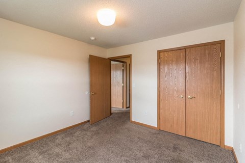an empty bedroom with a closet and a door to a hallway