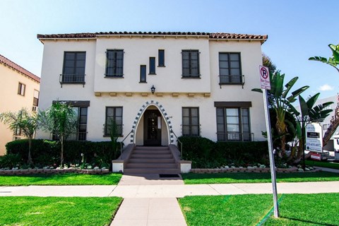 A white building with a red roof and a sign on the right side.