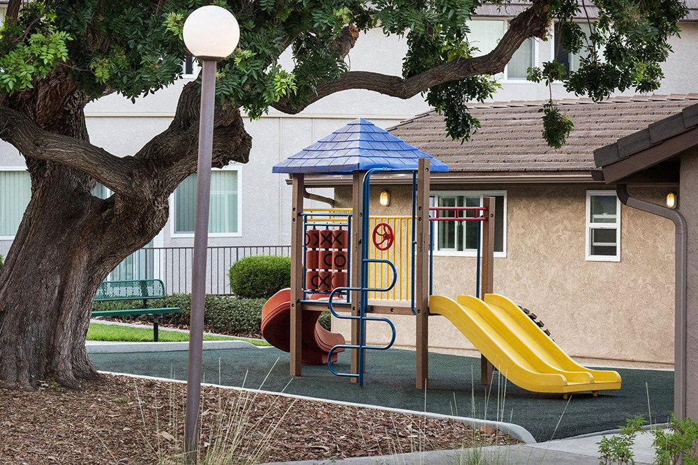 a playground with a swing set in front of a building