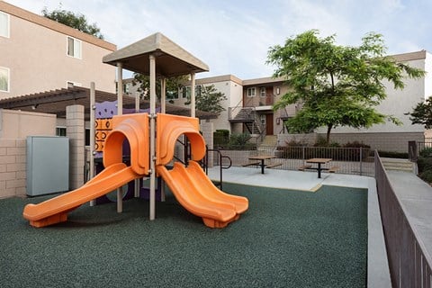a childrens play area with an orange slide and a playground