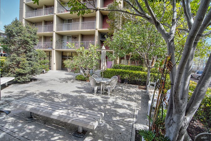 a bench and chairs in a courtyard in front of an apartment building