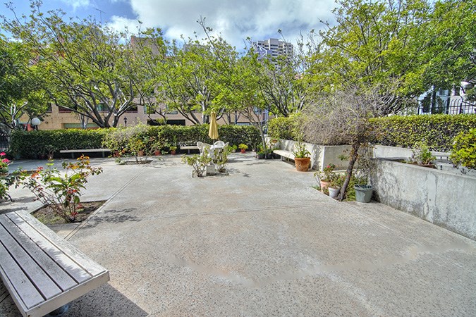 a courtyard with trees and a wooden bench