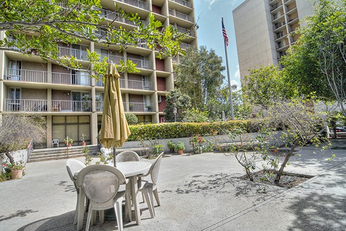 a patio with a table and chairs in front of an apartment building