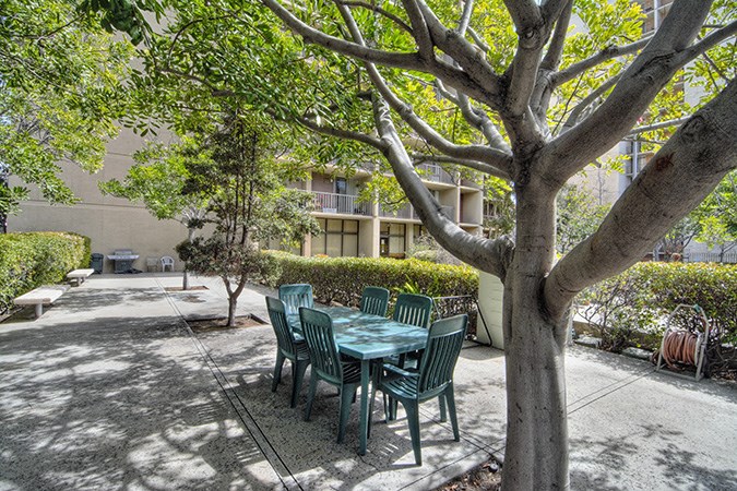 a patio with a table and chairs under a tree