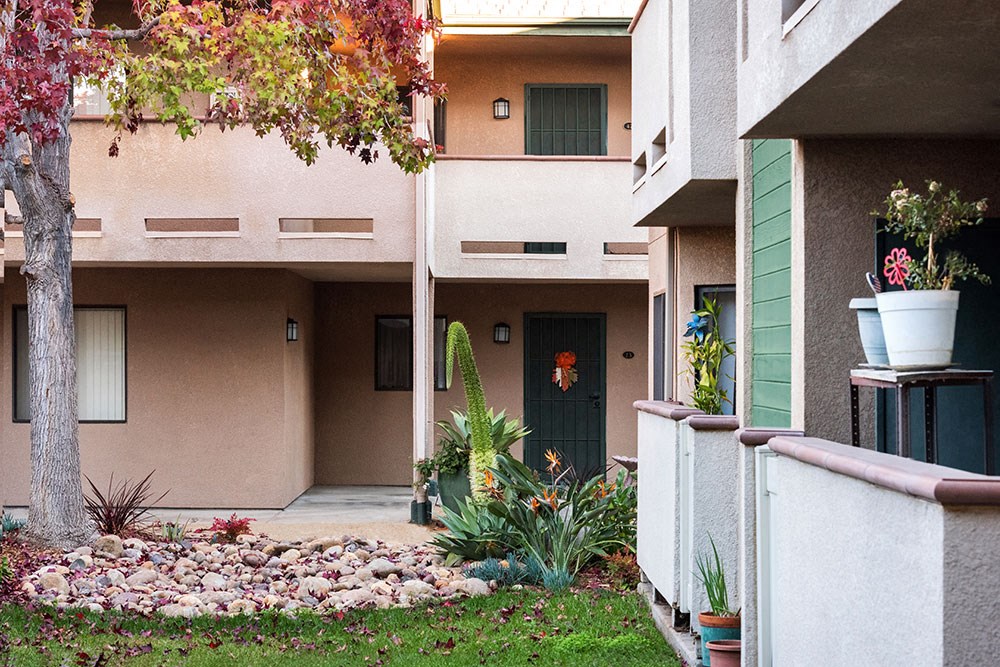 the entrance to an apartment building with a gravel pathway and plants