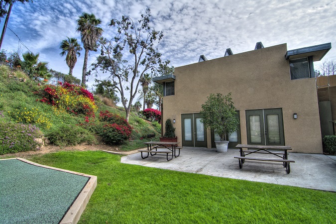 a patio with two benches and a table in front of a house