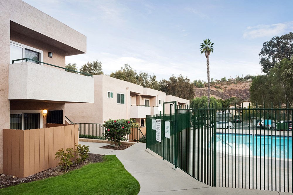a pool in front of a house with a green fence