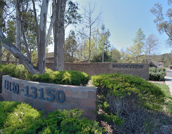a brick retaining wall with a sign that reads moonwehr and a building behind