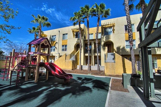 a playground in front of a building with palm trees