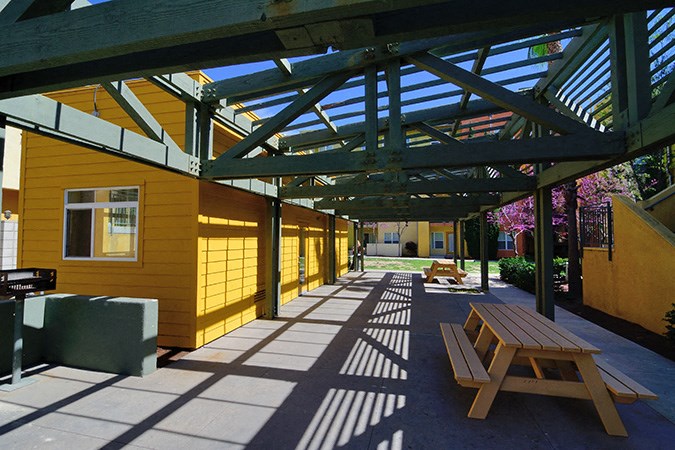 a covered patio with a picnic table and benches