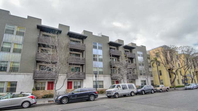 a row of apartment buildings with cars parked in front of them