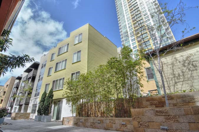 a yellow building with trees in front of a tall building
