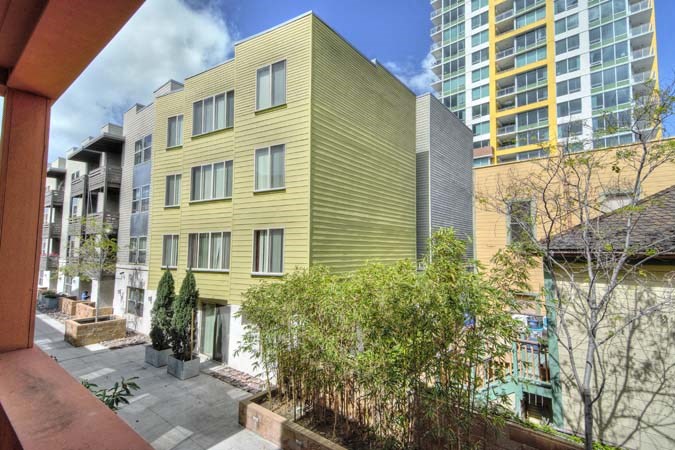 a yellow building with a courtyard in front of tall buildings