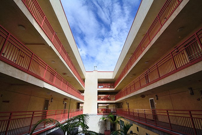 an empty building with red balconies and a blue sky