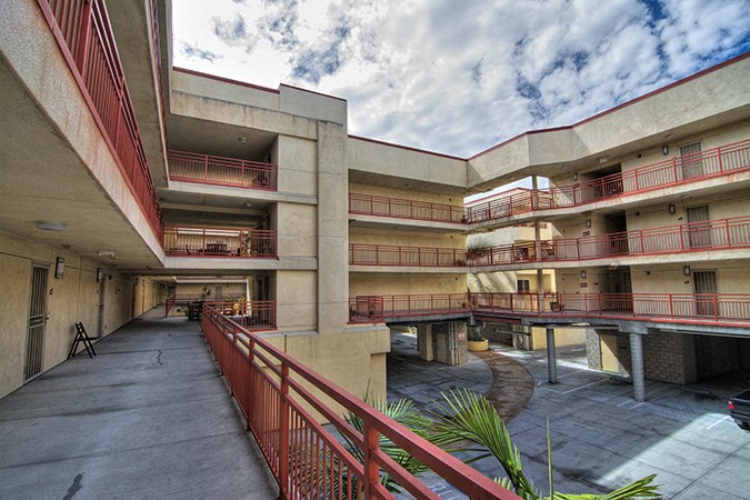 an exterior view of an apartment building with red balconies and a courtyard