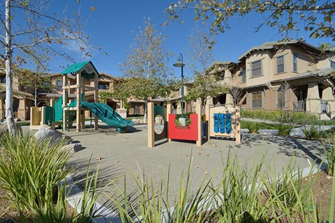 a childrens playground in a park in front of houses