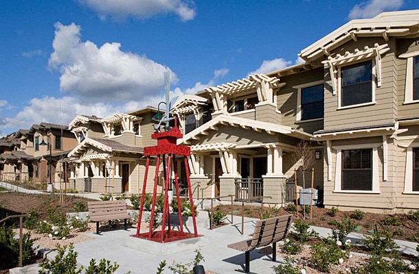 a red sculpture in a courtyard in front of a row of houses