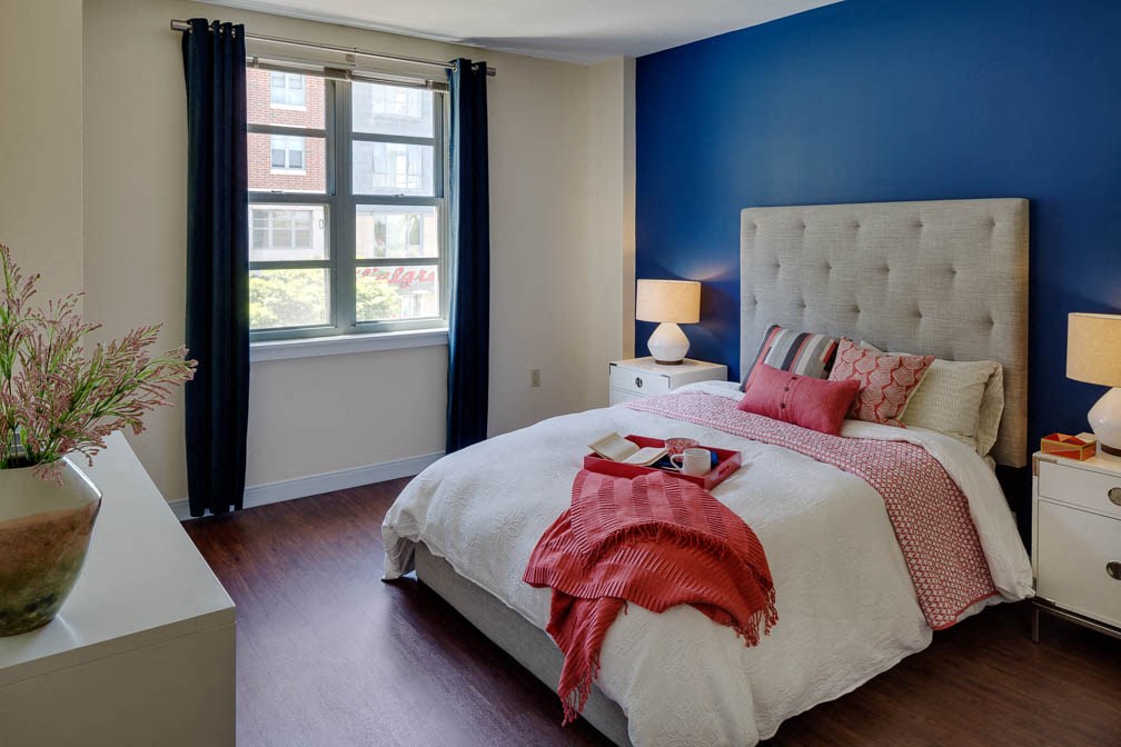 a bedroom with a bed and a blue wall and a window