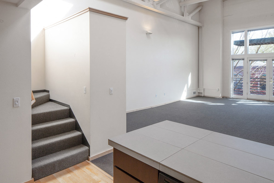 a living room with white walls and a staircase and a table
