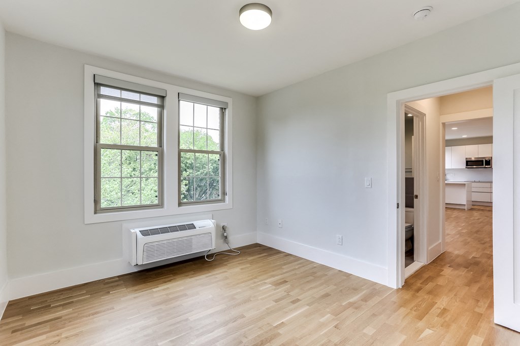 an empty living room with a wood floor and a window