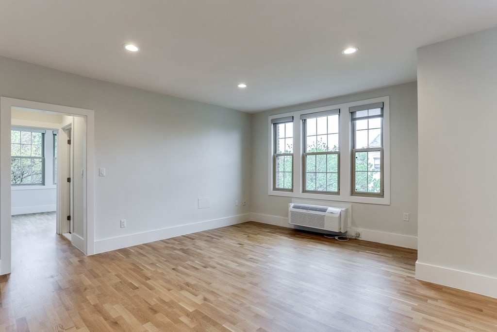 an empty living room with white walls and a wood floor