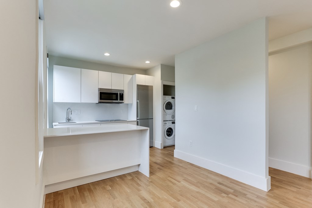 a kitchen with white cabinets and a washer and dryer and a laundry room