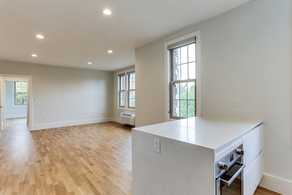 an open kitchen and living room with wood flooring and a large window