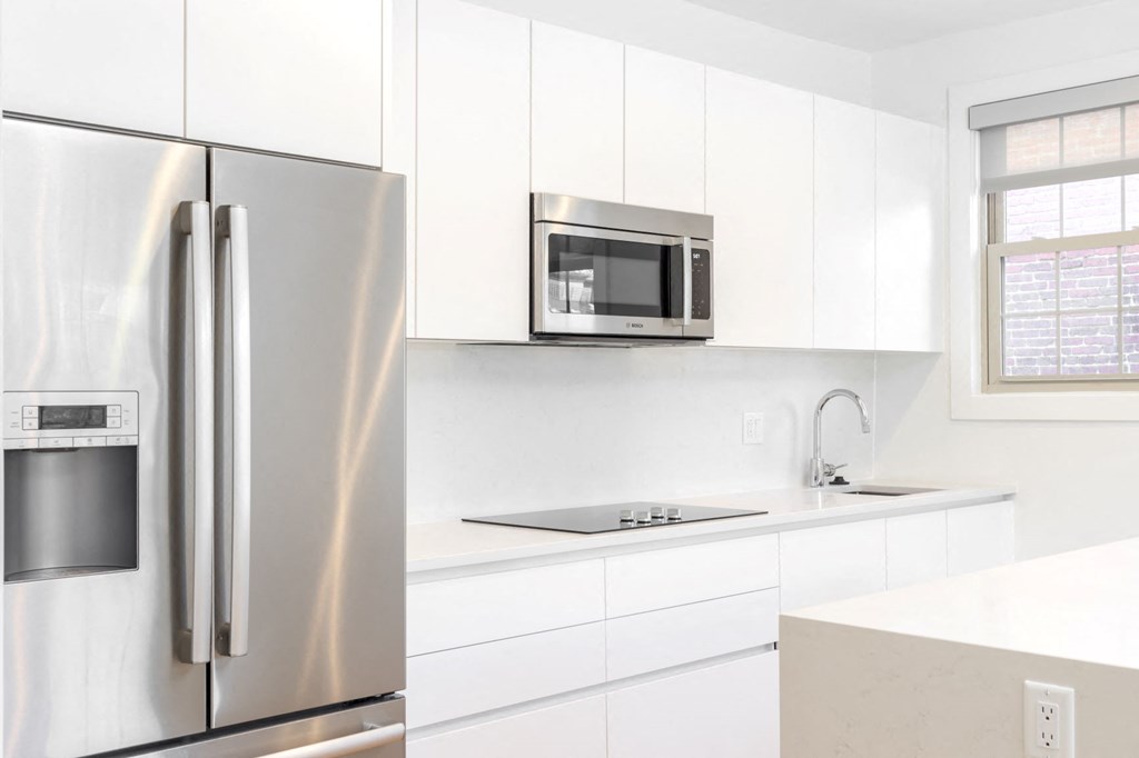 a white kitchen with a stainless steel refrigerator