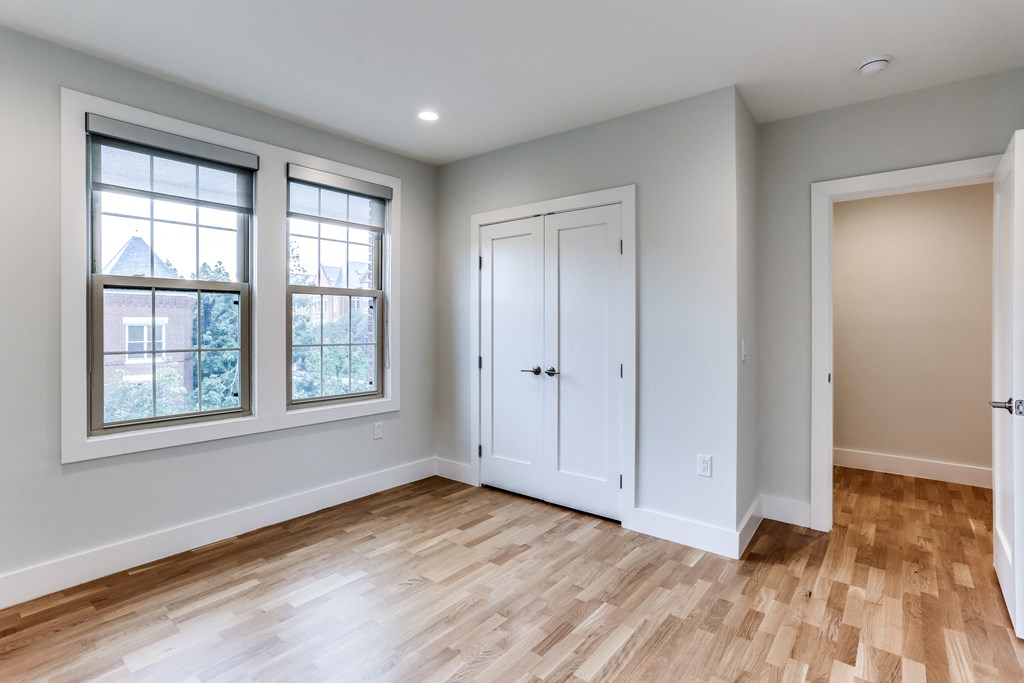 an empty room with wooden floors and white doors and windows