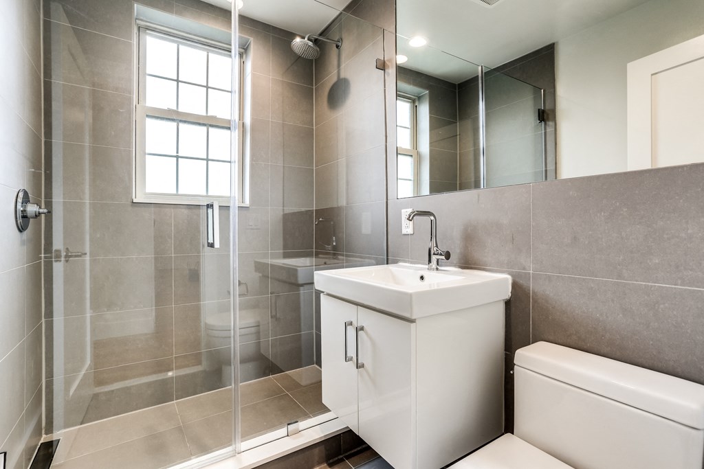 a bathroom with a shower sink and mirror and a toilet